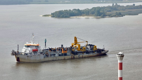 Das Baggerschiff "James Cook" fährt auf der Elbe zwischen dem Leuchtturm Blankenese und einer Insel des Naturschutzgebiets Neßsand flussaufwärts. © picture alliance / dpa Foto: Georg Wendt