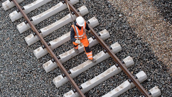Ein Arbeiter geht in Hamburg über eine Gleisanlage der Bahn. © dpa Foto: Lukas Schulze