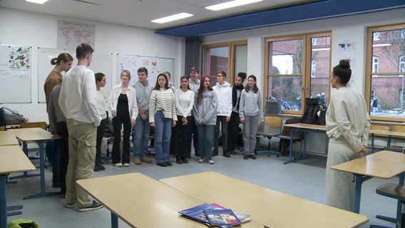 Mehrere Jugendliche stehen in einem Klassenraum. © Screenshot 