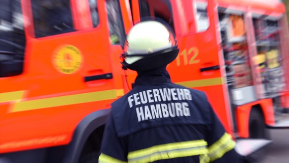 Ein Feuerwehrmann steht vor einem Löschfahrzeug. © picture alliance/dpa Foto: Daniel Bockwoldt