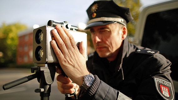 Ein Hamburger Polizist steht hinter einem Tempomessgerät. © dpa Foto: Axel Heimken