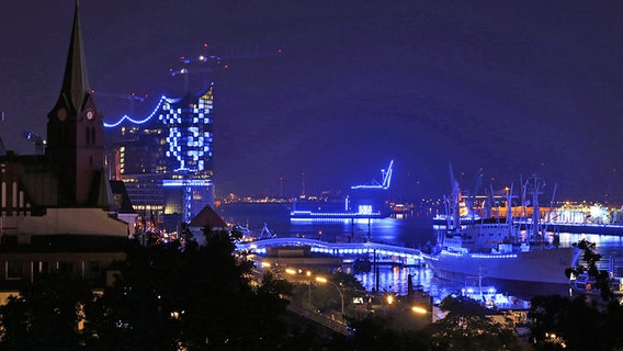 Der Hafen ist blau beleuchtet - auch die Elbphilharmonie im Hintergrund. © Imago Foto: Imago/Strussfoto