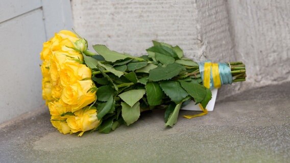 Gelbe Blumen liegen vor dem ukrainischen Konsulat in Hamburg. © picture alliance / dpa Foto: Jonas Walzberg