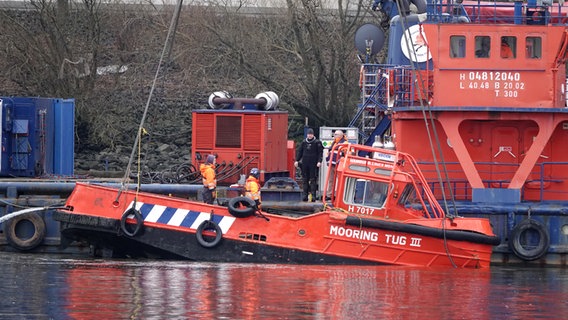 Ein Festmacherboot, das in der Nähe der Köhlbrandbrücke im Hamburger Hafen gesunken ist, wird mit einem Kran aus dem Wasser geborgen. © picture alliance / dpa Foto: Rabea Gruber