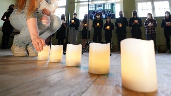 Kerzen stehen beim Gedenken der getöteten Kinder am Bullenhuser Damm auf dem Boden. © picture alliance/dpa Foto: Marcus Brandt
