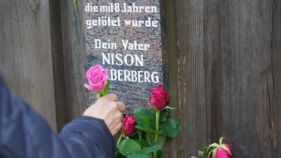 Eine Frau steckt Rosen an den Gedenktafeln der getöteten Kinder im Rosengarten der Gedenkstätte Bullenhuser Damm. © picture alliance/dpa | Marcus Brandt Foto: Marcus Brandt