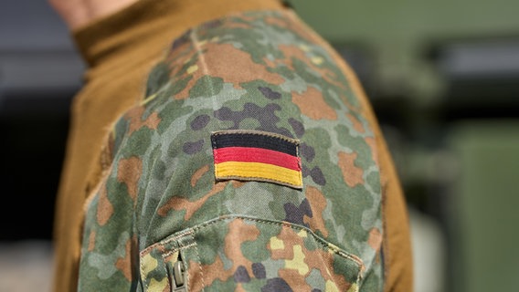 Soldat der deutschen Bundeswehr in Uniform vor einem Militärfahrzeug. Deutschland Flagge auf der Schulter der Bundeswehruniform © picture alliance / CHROMORANGE | Michael Bihlmayer Foto: Michael Bihlmayer
