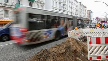 Ein Bus fährt in der Straße Mühlenkamp im Stadtteil Winterhude in Hamburg an einer Baustelle vorbei. © dpa Fotograf: Bodo Marks