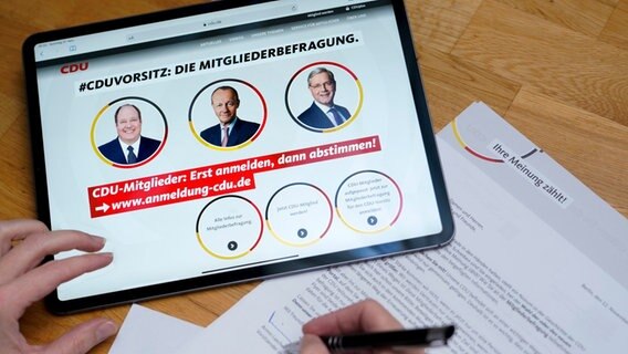 Auf einem Tablet sind die drei Kandidaten für den CDU-Parteivorsitz abgebildet: Norbert Roettgen, Friedrich Merz und Helge Braun. © picture alliance/Flashpic Foto: Jens Krick