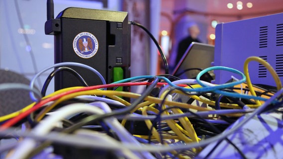 Bunte Kabel vor einem schwarzen Gerät mit einem Sticker der NSA. © NDR Foto: Carolin Fromm