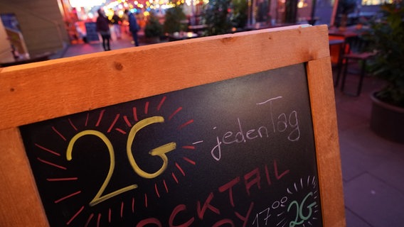 "2G - jeden Tag" steht auf einer Tafel vor einer Bar am Spielbudenplatz auf St. Pauli. © picture alliance/dpa Foto: Marcus Brandt