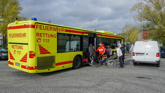 Mehrere Personen begeben sich in einen Großraumrettungswagen der Feuerwehr. © CityNewsTV 