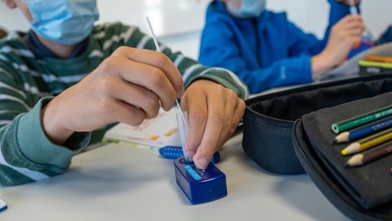 Zwei Schulkinder machen im Klassenraum einen Corona-Schnelltest. © dpa Foto: Peter Kneffel