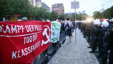 Polizisten und Demonstranten mit Transparenten stehen sich am 29.06.2017 bei einer Demonstration von G20-Gipfel-Gegnern auf der Reeperbahn in Hamburg gegenüber. © dpa - Bildfunk Foto: Bodo Marks