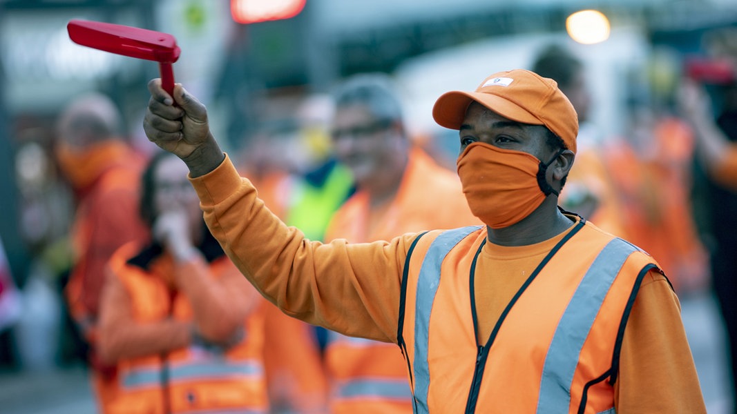 Eine Mitarbeiter der Hamburger Stadtreinigung steht bei einer Kundgebung der Gewerkschaft ver.di zu Warnstreiks im öffentlichen Dienst auf dem Jungfernstieg.