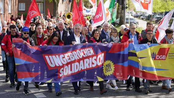 "Ungebrochen solidarisch" steht auf einem Transparent hinter dem die Teilnehmer einer Demonstration der Gewerkschaften zum 1. Mai 2023 in Hamburg laufen. © picture alliance / dpa Foto: Marcus Brandt