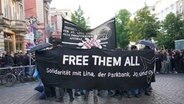Zahlreiche Menschen haben sich zu einer Demonstration vor der Roten Flora im Hamburger Schanzenviertel versammelt. Auf einem Transparent steht "Free them all". © picture alliance / dpa Foto: Marcus Brandt
