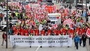 Bei einer Demonstration gegen den Verkauf von HHLA-Anteilen tragen Teilnehmende ein Transparent mit der Aufschrift "Kein Verkauf von Stadteigentum! Unser Hafen - Nicht Euer Casino!" © Bodo Marks/dpa 