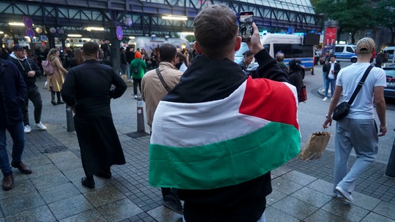 Ein junger Mann trägt bei eine palästinensische Flagge über den Schultern. © picture alliance 