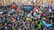 Mit Fahnen und Plakaten stehen die Demonstrierenden auf der Ludwig-Erhard-Straße vor der Bühne. © dpa Foto: Jonas Walzberg