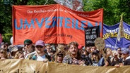 Teilnehmer halten bei einer 1.Mai-Demo mit dem Motto "Superreiche? Superscheiße!" in Hamburg ein Transparent mit der Aufschrift "Umverteilen!!". © picture alliance / dpa Foto: Markus Scholz