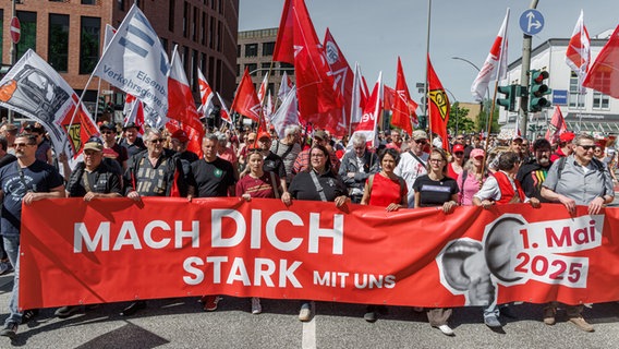 Mehrere Menschen versammeln sich bei einer Kundgebung des Deutschen Gewerkschaftsbundes am 1. Mai hinter einem Transparent. © dpa Foto: Markus Scholz