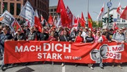 Mehrere Menschen versammeln sich bei einer Kundgebung des Deutschen Gewerkschaftsbundes am 1. Mai hinter einem Transparent. © dpa Foto: Markus Scholz