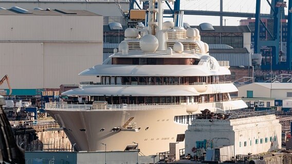 Von der Abendsonne beschienen liegt die Mega-Jacht "Dilbar" im Blohm+Voss Dock Elbe 17 im Hafen. © picture alliance/dpa Foto: Markus Scholz