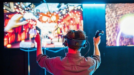Im Discovery Dock in Hamburg steht ein Mann an einer VR-Station, bei der Besucher virtuell an Konzerten teilnehmen können. © picture alliance / dpa Foto: Daniel Reinhardt