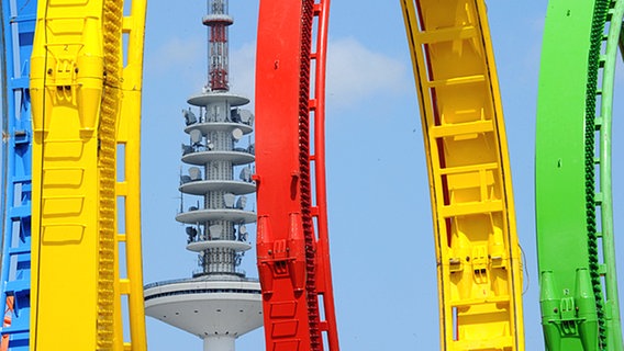 Der Hamburger Fernsehturm ist zwischen Loopings einer Achterbahn zu sehen. © dpa Foto: Angelika Warmuth