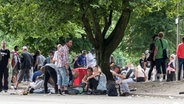 Viele Menschen stehen und sitzen im August-Bebel Park vor der Kontakt- und Beratungsstelle "Drob Inn". © Markus Scholz Foto: Markus Scholz