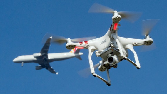 Eine private Drohne fliegt über einem Garten, in weiter Entfernung ist ein Flugzeug zu sehen. © picture-alliance / dpa Foto: Julian Stratenschulte