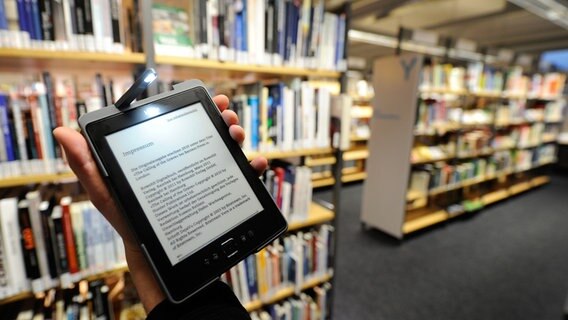 Jemand guckt sich ein E-Book auf einem Tablet in einer Bibliothek an. © picture alliance / dpa | Axel Heimken Foto: Axel Heimken