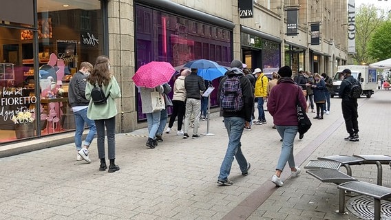 Menschen stehen vor Geschäften in der Hamburger Innenstadt Schlange  