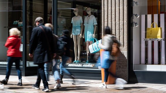 Passanten gehen am Schaufenster einer Boutique in Hamburg vorbei. © dpa Foto: Daniel Reinhardt