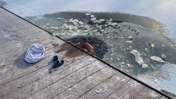 Ein Mann badet in einem Loch im Eis. © NDR Foto: Astrid Botsch