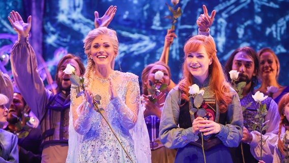 Sabrina Weckerlin (als Eiskönigin Elsa, Mitte, links), Celena Pieper (als Anna, die Schwester der Eiskönigin, Mitte, rechts), und weitere Musicaldarsteller stehen nach der Deutschland-Premiere des Disney-Musicals "Die Eiskönigin" auf der Bühne im Stage Theater an der Elbe in Hamburg. © picture alliance / dpa Foto: Christian Charisius