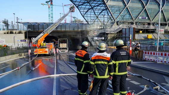 Feuerwehrleute stehen für der S-Bahnbrücke Elbbrücken, an der ein Lkw ausgebrannt ist. © dpa 