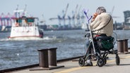 Eine alte Frau sitzt an der Elbe auf den Landungsbrücken auf ihrem Rollator. © dpa Foto: Markus Scholz