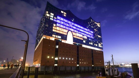 Einige Fenster in der Fassade der Elbphilharmonie sind am Abend in den Farben der Ukraine beleuchtet. © picture alliance/dpa Foto: Christian Charisius