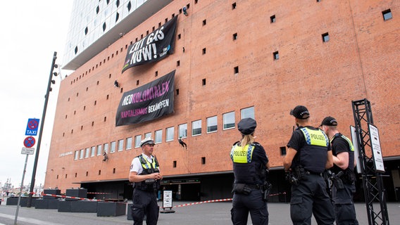 An der Fassade der Elbphilharmonie hängen Banner, die Klima-Aktivisten dort entrollt haben. © Daniel Bockwoldt/dpa 