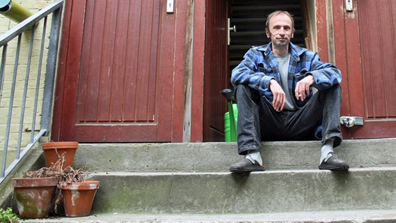 Bernd Gohlke sitzt vor dem Eingang zu seiner Wohnung in einem der Elbtreppenhäuser.  