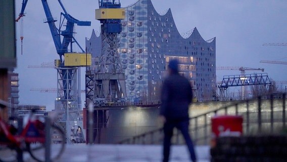 Ein Mann geht in der Nähe der Elbphilharmonie spazieren. © picture alliance/dpa Foto: Marcus Brandt