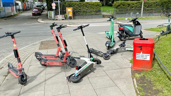 Numerous e-scooters are on a sidewalk in Hamburg.  