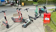 Zahlreiche E-Scooter stehen in Hamburg auf einem Bürgersteig.  