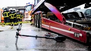 Ein E-Scooter liegt auf der Straße neben einem Lkw. Im Hintergrund Einsatzkräfte der Feuerwehr. © Daniel Bockwoldt/dpa Foto: Daniel Bockwoldt
