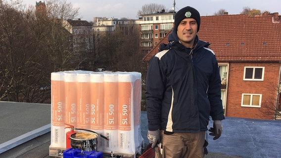 Auszubildender Karim Fattahi steht auf dem Dach eines Hauses in Hamburg.  