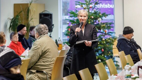 Hamburgs Bischöfin Kirsten Fehrs liest in der Tagesaufenthaltsstätte für Wohnungslose der Diakonie die Weihnachtsgeschichte und singt mit den Besuchern Weihnachtslieder. © picture alliance/dpa | Markus Scholz Foto: picture alliance/dpa | Markus Scholz