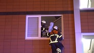 Die Feuerwehr Hamburg rettet zwei Kinder über eine Steckleiter aus einer verqualmten Wohnung. © NDR 