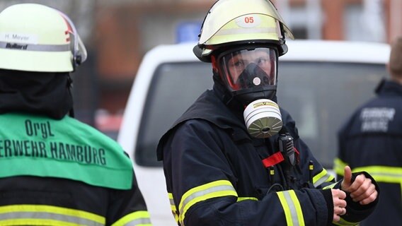 Ein Feuerwehrmann trägt eine Gasmaske bei einem Einsatz wegen eines Großbrandes in Hamburg-Rothenburgsort. © Jonas Walzberg/dpa 